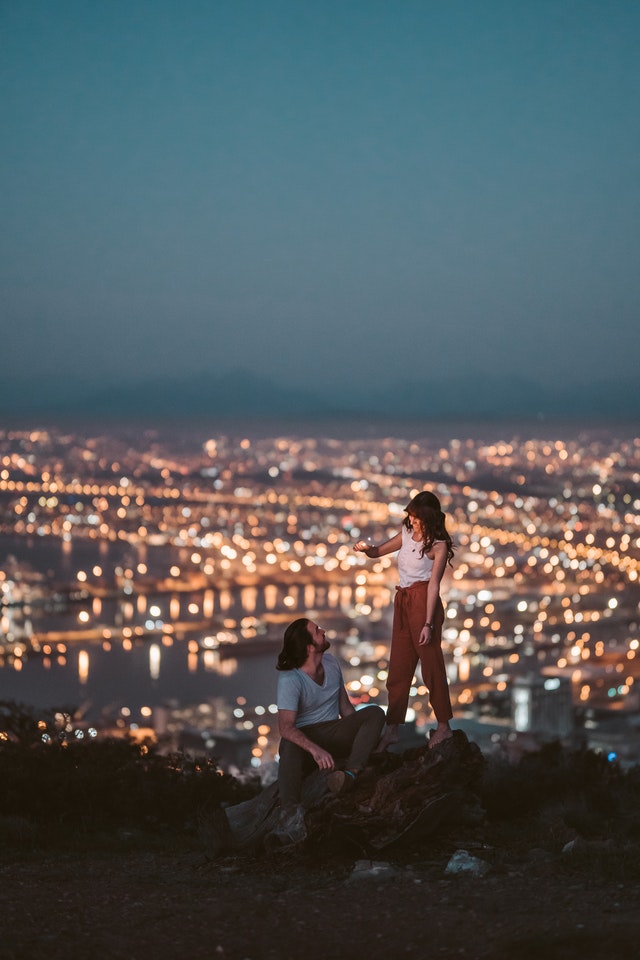 Ein Paar in einer Beziehung vor einer Stadt auf einem Berg. 